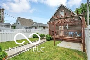 back of house with a wooden deck and a lawn