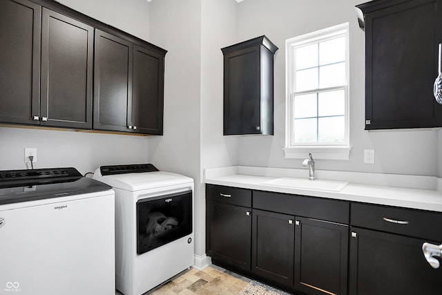 laundry area with independent washer and dryer, cabinet space, a sink, and stone finish flooring