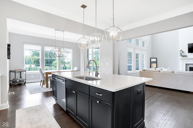 kitchen featuring dark cabinets, a fireplace, a sink, stainless steel dishwasher, and dark wood-style floors