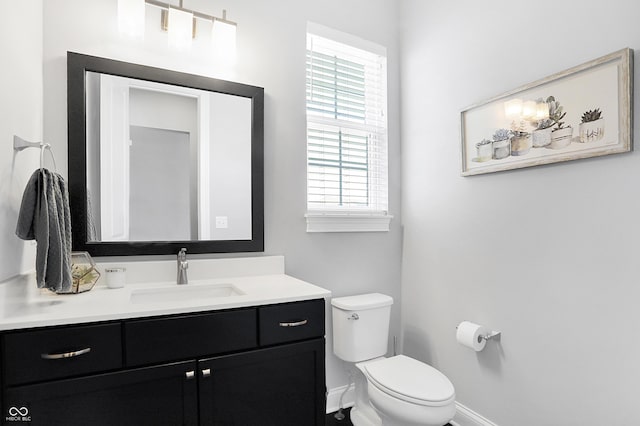 bathroom featuring toilet, baseboards, and vanity