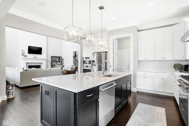 kitchen with stainless steel appliances, a fireplace, a sink, and white cabinets