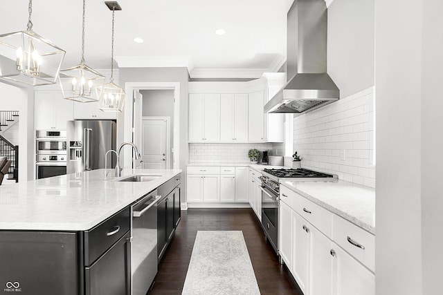 kitchen featuring range hood, ornamental molding, a kitchen island with sink, a sink, and high quality appliances