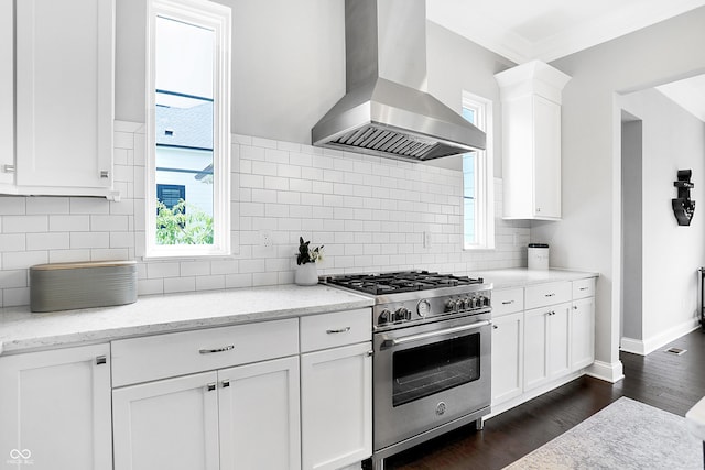 kitchen featuring dark wood-style floors, tasteful backsplash, high end stainless steel range oven, white cabinetry, and wall chimney exhaust hood