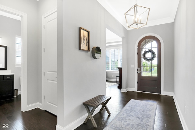 entryway featuring a chandelier, arched walkways, dark wood-style flooring, and baseboards