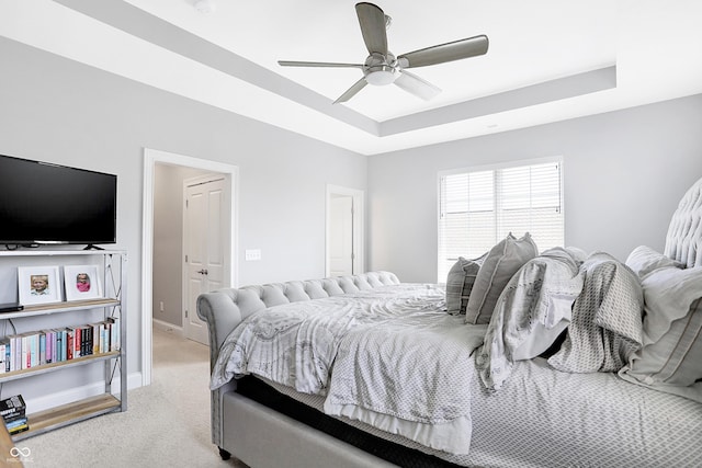 bedroom with baseboards, ceiling fan, a raised ceiling, and light colored carpet