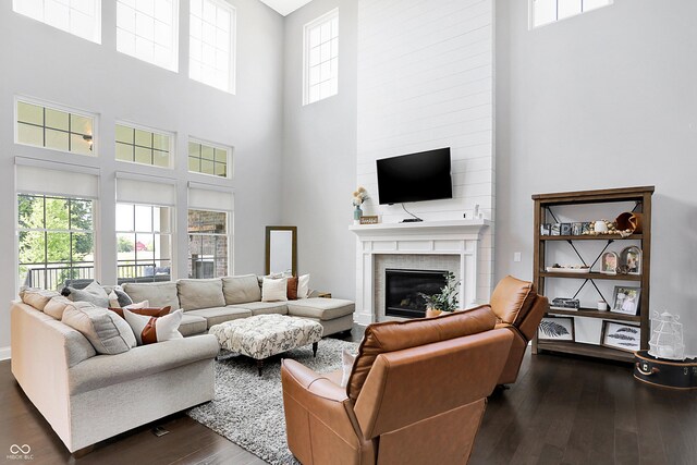 living room with a large fireplace and dark wood-style flooring