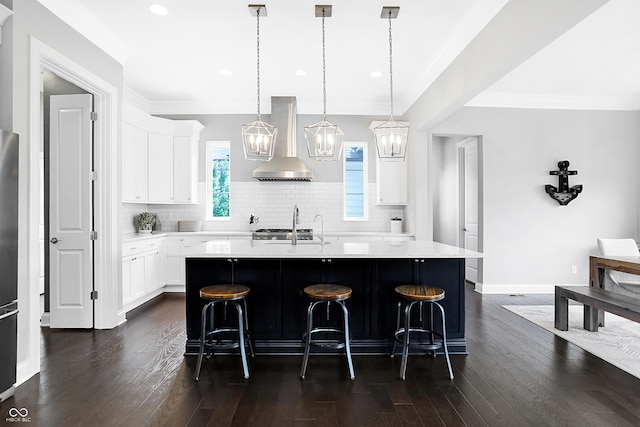 kitchen featuring a kitchen bar, light countertops, dark wood finished floors, and wall chimney exhaust hood