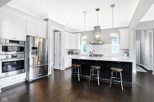 kitchen with decorative backsplash, dark wood-style floors, wall chimney exhaust hood, stainless steel appliances, and a kitchen bar