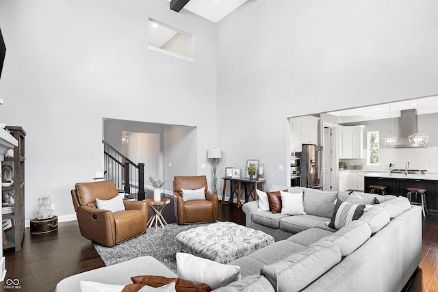 living room with a high ceiling, stairway, dark wood finished floors, and baseboards