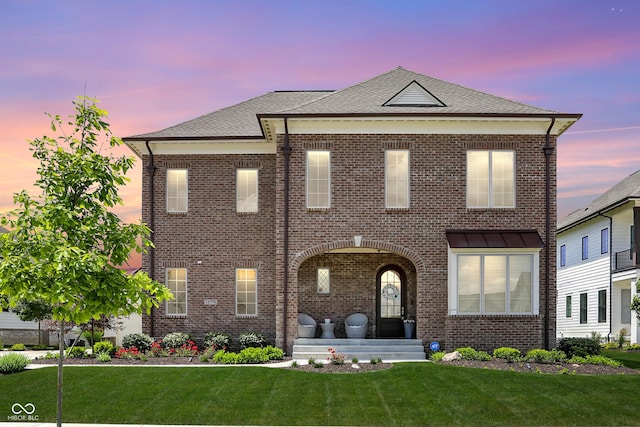 view of front of home with brick siding, a shingled roof, and a front yard