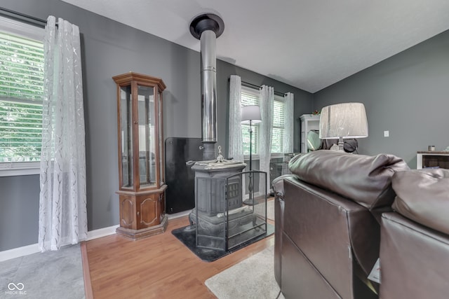 interior space featuring a wood stove, baseboards, vaulted ceiling, and wood finished floors