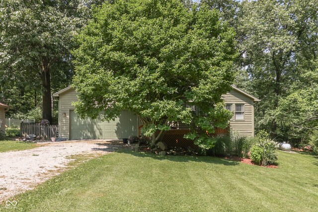 view of property hidden behind natural elements featuring a garage and a front lawn