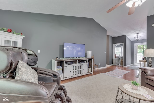 living room featuring baseboards, vaulted ceiling, wood finished floors, and ceiling fan with notable chandelier