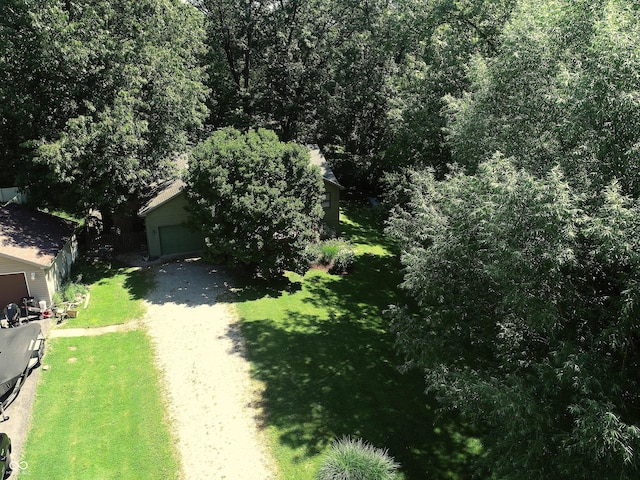 exterior space featuring driveway, a garage, a front lawn, and an outbuilding