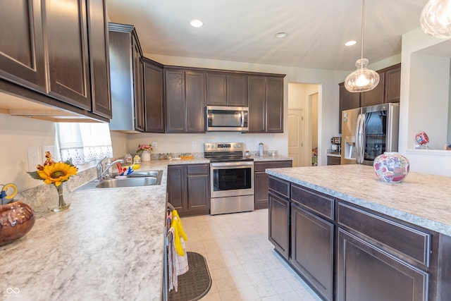 kitchen with dark brown cabinets, stainless steel appliances, light tile flooring, hanging light fixtures, and sink