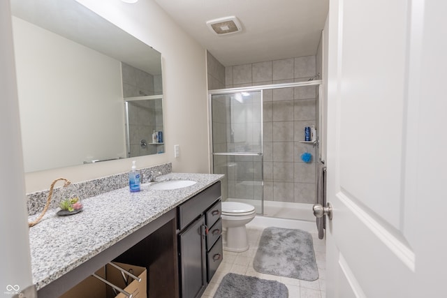 bathroom with a shower with shower door, tile floors, large vanity, and toilet