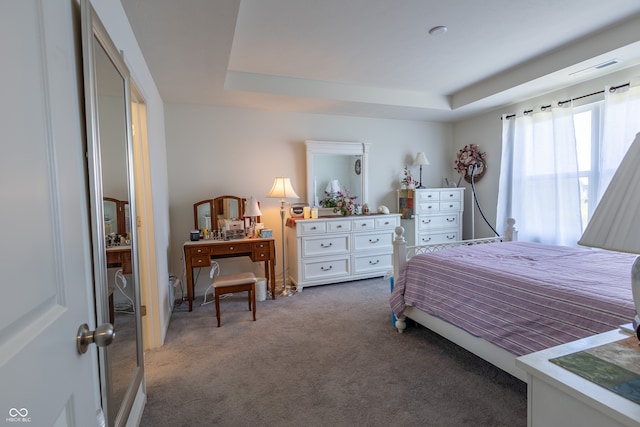 bedroom with a tray ceiling and dark carpet