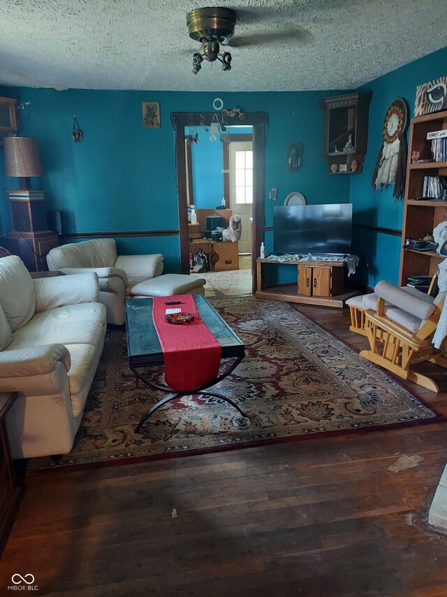 living room featuring a textured ceiling, ceiling fan, and dark hardwood / wood-style floors