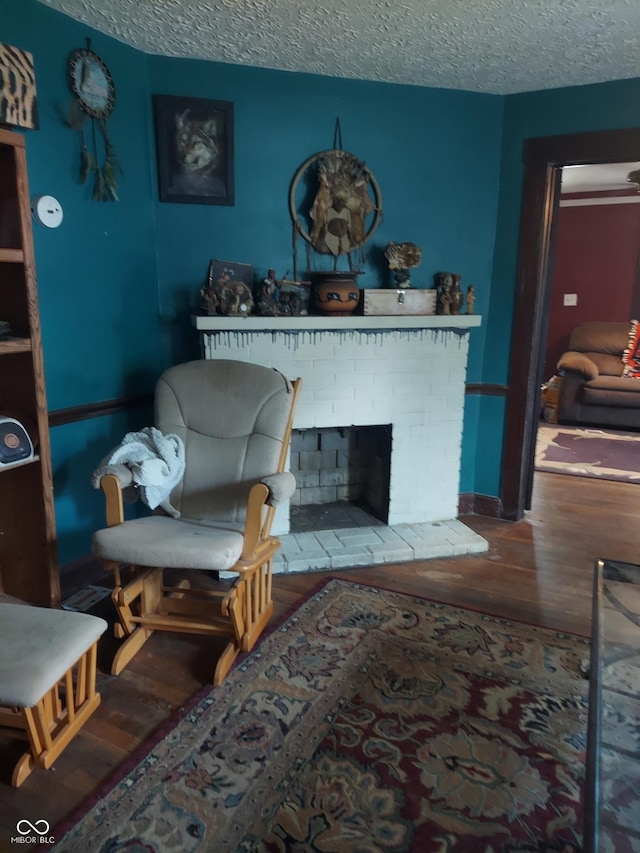 living room featuring a textured ceiling, a brick fireplace, and wood-type flooring