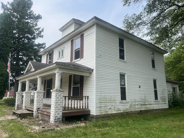 view of side of home with a yard and covered porch