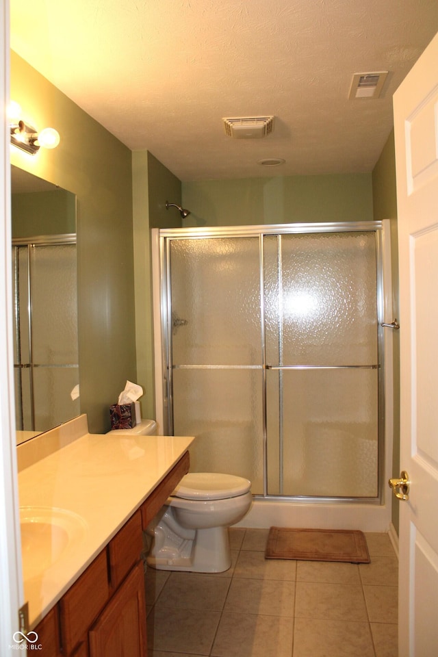 bathroom featuring tile patterned flooring, vanity, toilet, and walk in shower