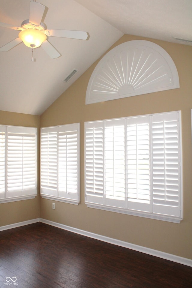 spare room with vaulted ceiling, a healthy amount of sunlight, and dark hardwood / wood-style flooring