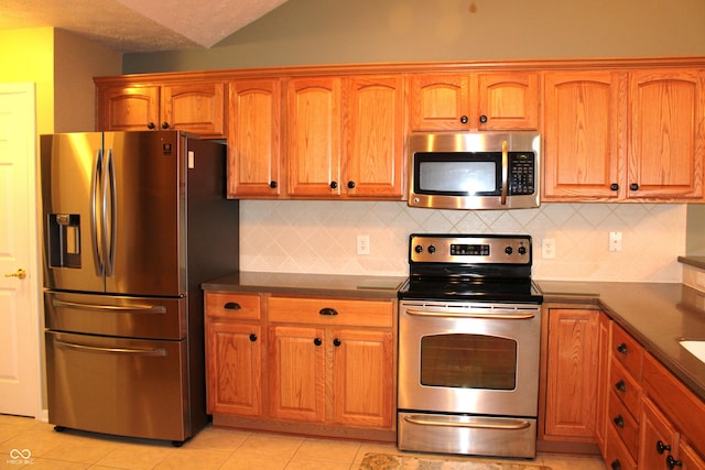 kitchen with backsplash, light tile patterned floors, stainless steel appliances, and a textured ceiling