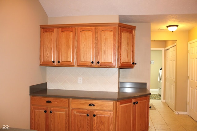 kitchen with washer / dryer, decorative backsplash, and light tile patterned floors