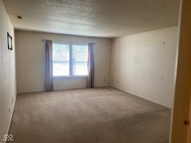 carpeted empty room featuring a textured ceiling