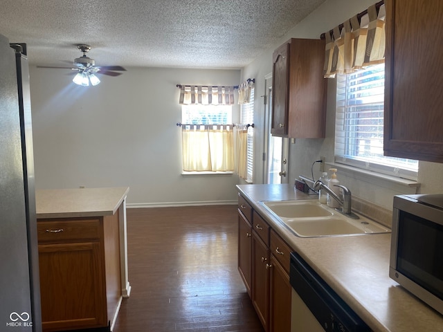 kitchen with a textured ceiling, stainless steel appliances, dark hardwood / wood-style floors, sink, and ceiling fan