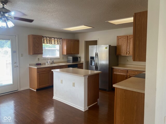 kitchen featuring dark hardwood / wood-style flooring, stainless steel appliances, ceiling fan, sink, and a textured ceiling