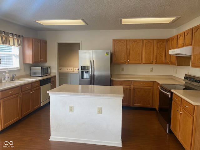 kitchen with a textured ceiling, dark hardwood / wood-style flooring, washer and clothes dryer, and appliances with stainless steel finishes