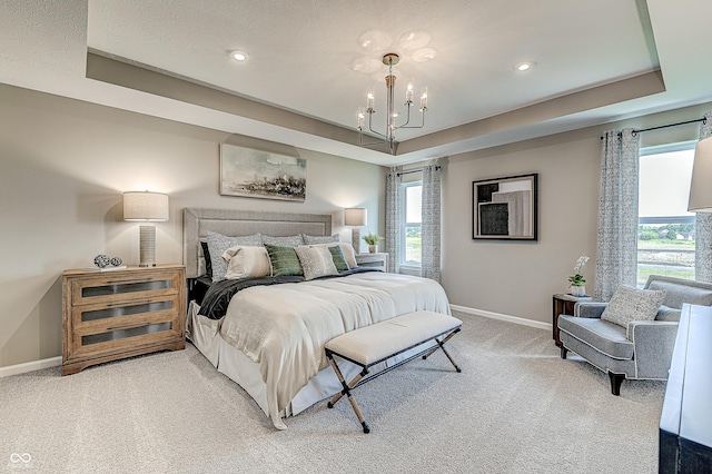 bedroom featuring carpet flooring, a tray ceiling, multiple windows, and a chandelier