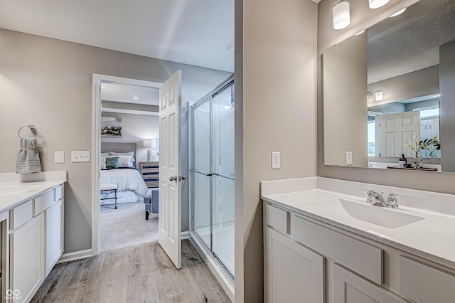 bathroom with a textured ceiling, vanity, wood-type flooring, and walk in shower