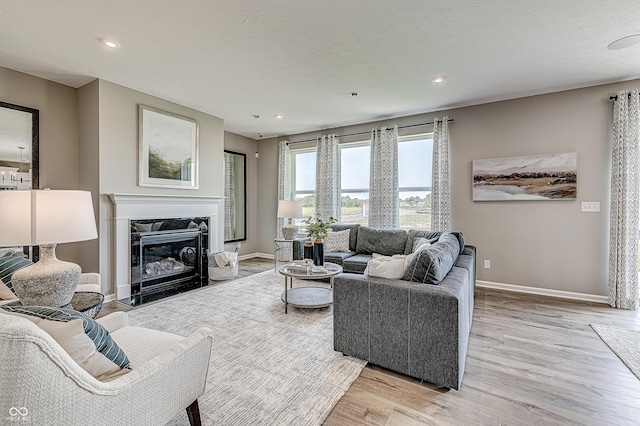 living room featuring a high end fireplace, a textured ceiling, and light hardwood / wood-style floors