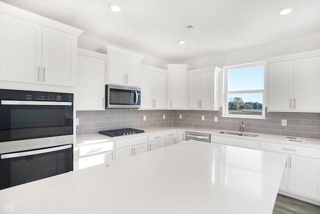 kitchen featuring white cabinets, sink, hardwood / wood-style flooring, decorative backsplash, and stainless steel appliances