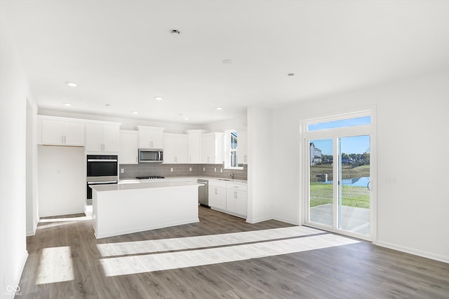 kitchen featuring light wood-type flooring, stainless steel appliances, sink, white cabinetry, and a kitchen island