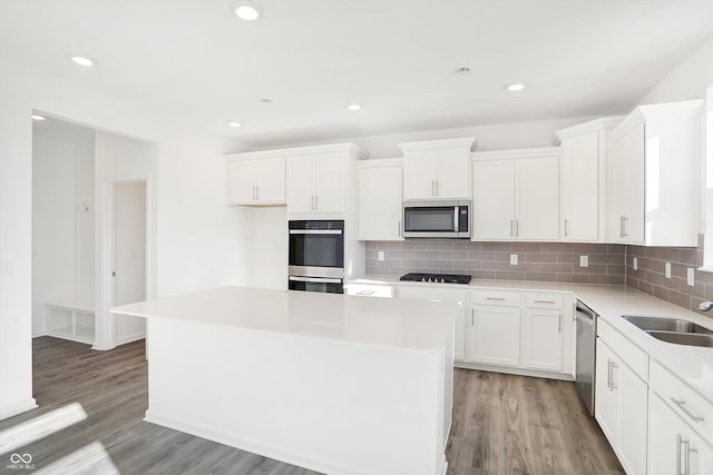 kitchen with white cabinets, appliances with stainless steel finishes, a kitchen island, and sink