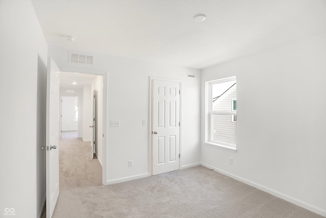 unfurnished bedroom featuring a closet and light colored carpet