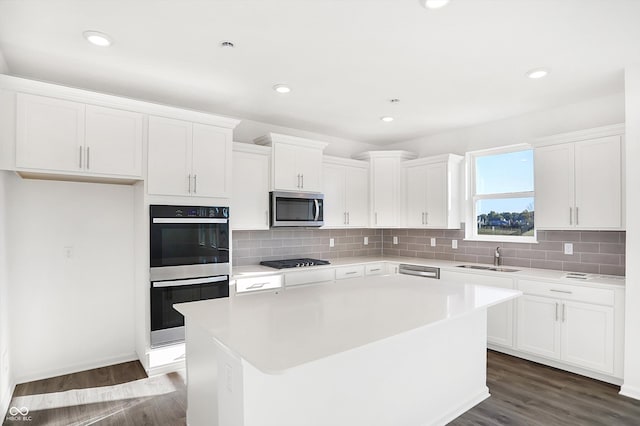 kitchen with appliances with stainless steel finishes, white cabinetry, and a kitchen island