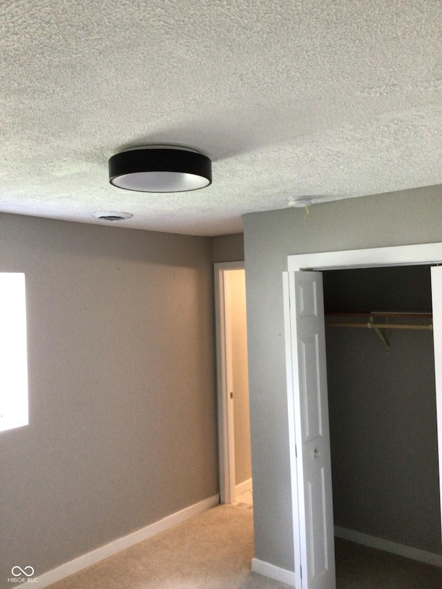 unfurnished bedroom featuring carpet floors, a closet, and a textured ceiling