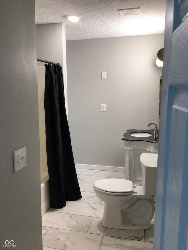 full bathroom featuring shower / bath combination with curtain, toilet, sink, and a textured ceiling