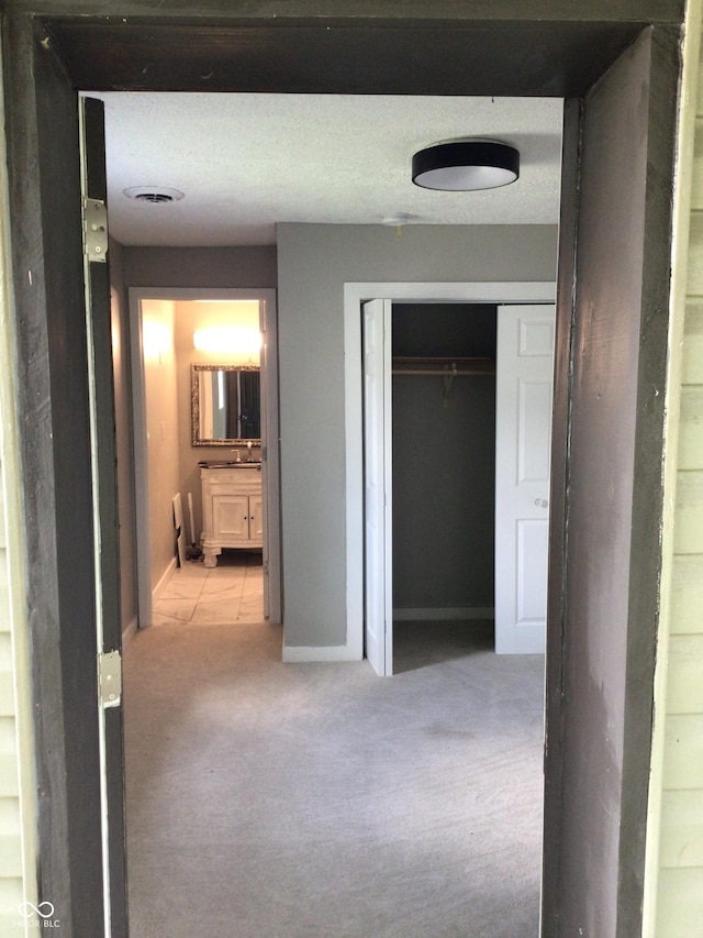 corridor featuring light carpet and a textured ceiling