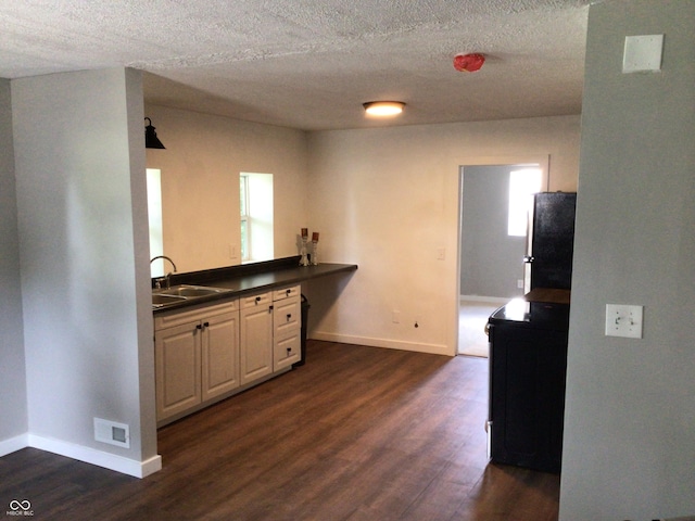 kitchen with sink, a textured ceiling, stainless steel refrigerator, dark hardwood / wood-style flooring, and white cabinets