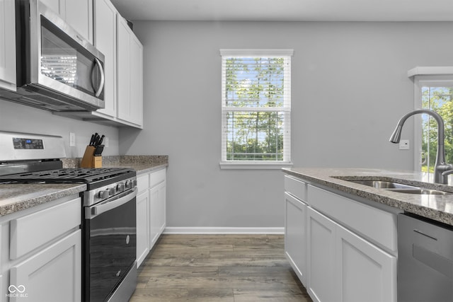 kitchen with plenty of natural light, appliances with stainless steel finishes, white cabinets, and a sink