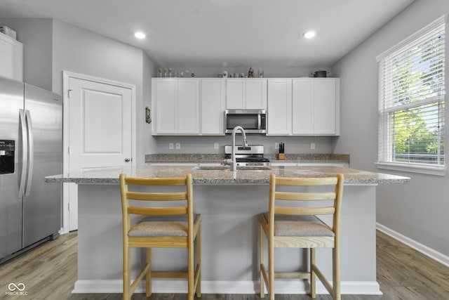 kitchen featuring white cabinets, a center island with sink, and stainless steel appliances