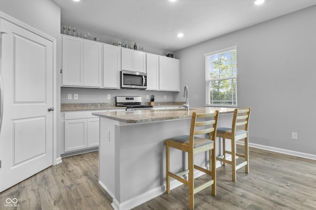 kitchen featuring stainless steel appliances, a center island with sink, and white cabinetry