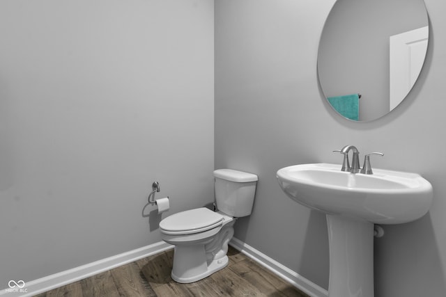 half bathroom with toilet, baseboards, and wood finished floors