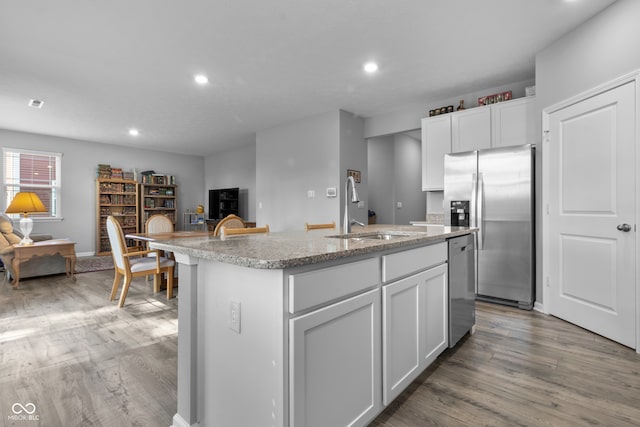 kitchen featuring white cabinetry, a center island with sink, appliances with stainless steel finishes, hardwood / wood-style flooring, and sink