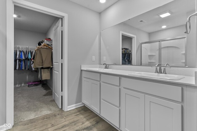 bathroom with dual bowl vanity, an enclosed shower, and hardwood / wood-style flooring